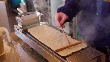 Close-up-of-a-person-kneading-traditional-pancake-or-crepe-dough-on-a-hot-plate