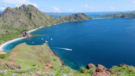Speedboat-moving-across-turquoise-blue-green-ocean-water-from-idyllic-secluded-bay-of-tropical-Padar-Island-in-Komodo-National-Park,-East-Nusa-Tenggara,-Indonesia
