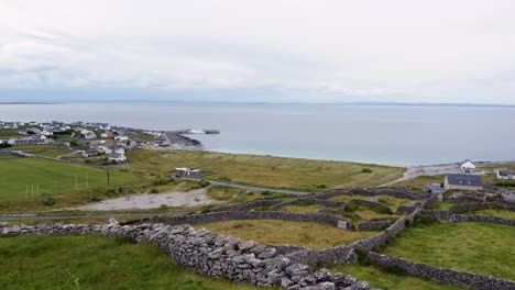 Rising-drone-shot-of-Inisheer-or-Inis-Oirr-Aran-Islands-showing-the-stone-walls-that-divide-fields-and-the-Inis-Oirr-ferry-birthed-in-the-harbour-Reminiscent-of-scenes-in-Banshees-of-Inisherin