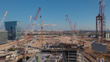 drone-push-in-shot-between-11-cranes-on-an-office-building-under-construction---sunny-day-without-clouds