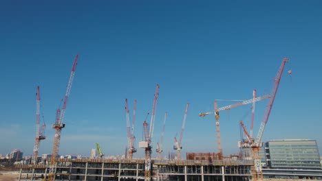 An-office-building-under-construction-with-11-cranes-on-it---parallax-tilt-up-shot
