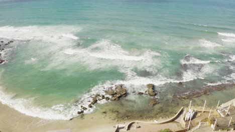 Oceanside-pool-in-Northern-Israel---Rocky-coastline,-crashing-waves-on-the-beach