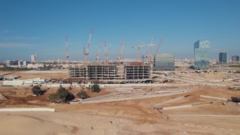 An-office-building-under-construction-with-many-cranes-on-it---push-in-shot