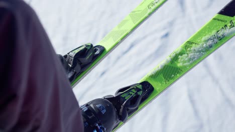 Close-up-of-boots-and-skis-of-a-person-going-up-the-chairlift-to-ski-on-a-snowy-slope-in-good-weather