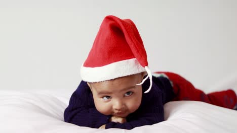 Kleiner-Junge-Mit-Weihnachtlicher-Roter-Mütze-Liegt-Im-Innenbereich-Mit-Niedlichem-Gesichtsausdruck-Und-Weißem-Hintergrund