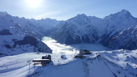A-drone-view-of-a-ski-resort-above-the-clouds-on-a-sunny-day-in-the-high-snowy-mountains