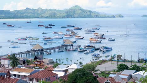 Panoramic-view-of-popular-tourism-destination-of-Labuan-Bajo-town,-marina,-wharf-and-moored-boats-awaiting-Komodo-National-Park-tours-on-Flores-Island,-Indonesia