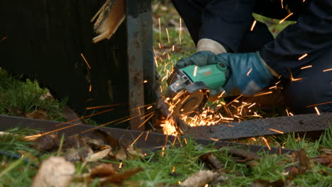 Worker-Using-Grinder-Creating-Bright-Sparks-on-Old-Metal-Whilst-Wearing-Protective-Gloves-and-Overalls