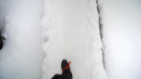 Walk-on-snow-in-mountains,-pov-view-on-a-narrow-snowy-road,-25-fps