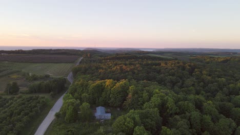 Aerial-view-of-a-summer-cottage-tucked-away-in-the-woods-near-the-scenic-M22-and-Sleeping-Bear-Dunes-and-Traverse-City-Michigan-at-sunset-with-the-light-kissing-the-tops-of-the-trees