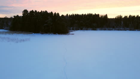 Person-standing-out-on-a-frozen-lake-in-sunset