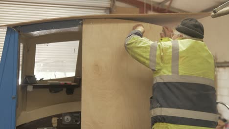 Shipwright-secures-bolts-on-new-plywood-bulkhead-in-fiberglass-boat