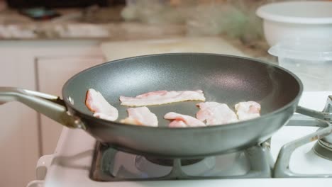 Bacon-frying-and-emitting-steam-over-a-low-flame-in-a-Teflon-pan