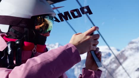 Skier-woman-taking-cell-phone-photos-of-snowy-mountain-scenery-from-inside-the-cableway