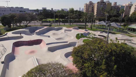 Parallax-shot-over-trees-of-a-big-skate-park-with-grass-around