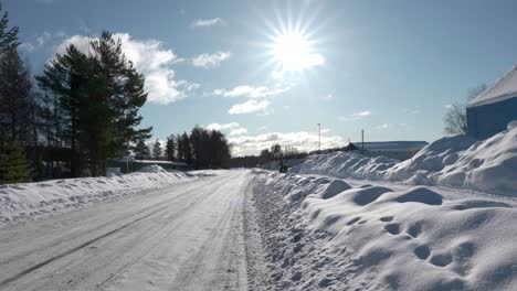 A-group-of-snowmobiles-driving-on-the-side-of-the-road,-on-cold-sunny-winter-day-in-Sweden