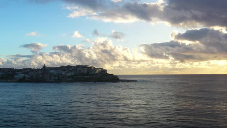 Drone-flying-over-Bondi-towards-a-boat-on-the-horizon-during-a-beautiful-sunrise
