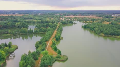 Drone-shot-of-a-lake-in-a-forest,-path-between-lakes