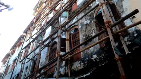 Kippende-Aufnahme-Eines-Heruntergekommenen-Gebäudes-In-Sansibar,-Das-Mit-Holzgerüsten-Repariert-Wird