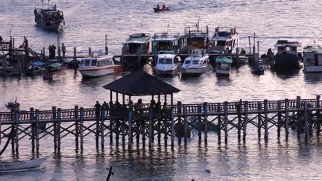 People-gathering-and-mingling-on-jetty-at-Labuan-Bajo-harbour-and-ocean-during-evening-twilight-sunset-in-Flores-Island,-Indonesia
