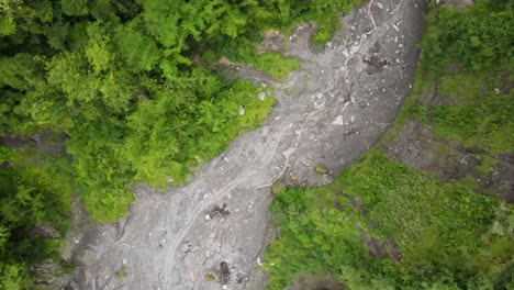 Aerial-view,-cold-lava-river-flow-of-Mount-Merapi,-and-visible-trucks-and-sand-miners-on-the-move