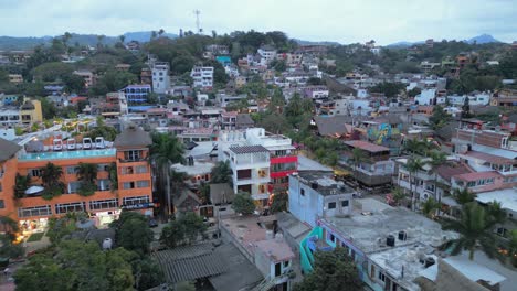 A-drone-pulls-back-in-flight-showing-the-expanse-of-the-town-of-Sayulita-Mexico-and-the-vibrant-colors-of-the-buildings