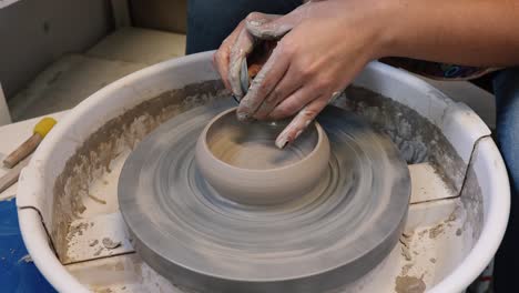Young-woman-in-pottery-studio-using-pottery-wheel,-handmade-ceramics,-creative