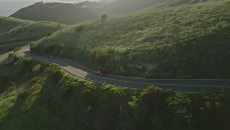 Beautiful-aerial-drone-shot-follows-a-red-Porsche-1993-Carrera-S-cruising-through-the-mountains-of-Malibu-at-golden-hour-sunset