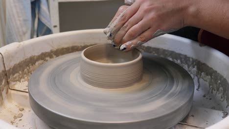 Young-woman-in-pottery-studio-using-pottery-wheel,-handmade-ceramics,-creative