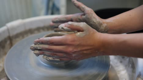 Young-woman-artist-making-clay-bowl-on-pottery-wheel
