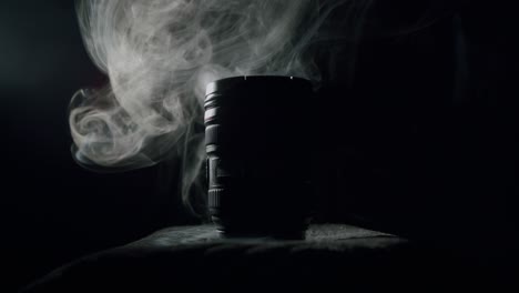 White-smoke-behind-a-modern-photography-lens-in-a-dark-room-in-a-silhouette-lighting