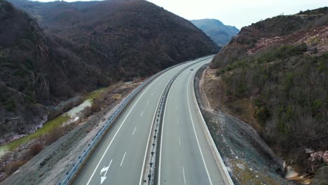 Flying-over-the-highway-where-cars-and-buses-pass-through-the-beautiful-mountain-valley-in-the-north-of-Albania