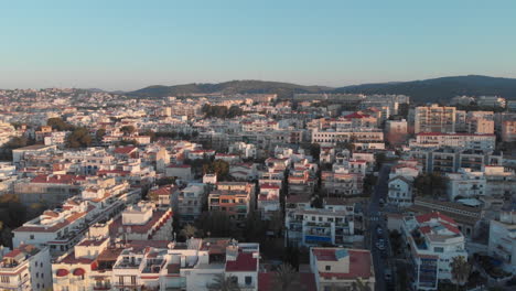 Aerial-drone-tilt-down-across-sunset-Spanish-cityscape-sky,-buildings-and-palms
