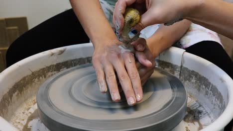 Young-woman-artist-making-clay-bowl-on-pottery-wheel