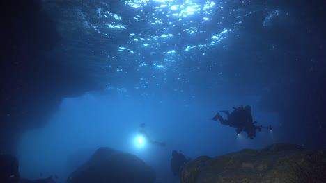 Divers-entering-an-underwater-cave-carrying-flashlights