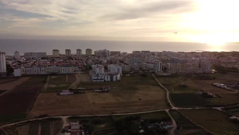 Aerial-view-of-Costa-da-Caparica-during-golden-sunset-behind-Atlantic-Ocean-in-Portugal---Wide-shot