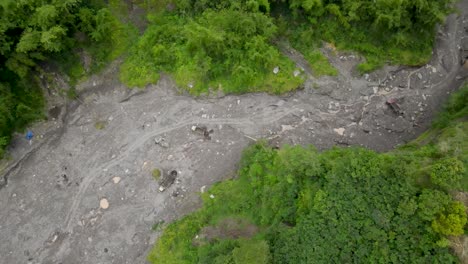 Aerial-view,-cold-lava-river-flow-of-Mount-Merapi,-and-visible-trucks-and-sand-miners-on-the-move