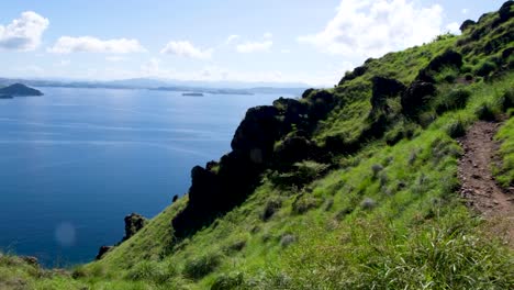 Steep-green-grass-covered-slopes-of-rocky-and-rugged-tropical-island-with-ocean-views-in-East-Nusa-Tenggara,-Indonesia
