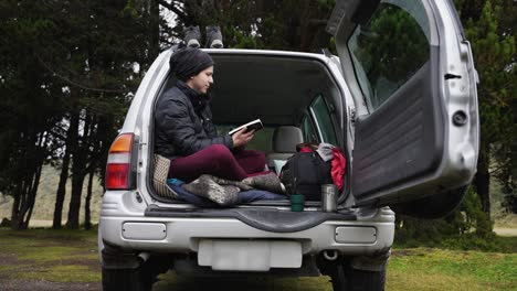 Glücklicher-Camper,-Der-Die-Natur-Genießt,-Während-Er-Im-Kofferraum-Eines-SUV-Ein-Buch-Liest
