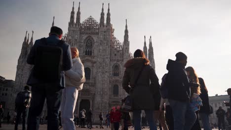 Frontal-view-of-Duomo-Milano-Cathedral-in-Milan-with-people-walking-on-open-square,-camera-movement,-downtown-view-of-Italian-city-with-tourists
