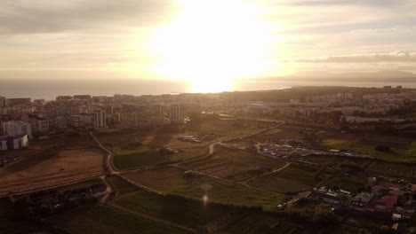 Beautiful-drone-shot-of-Costa-da-Caparica-with-bright-sunset-at-horizon-in-Portugal