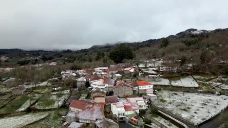 Snowy-village-with-vegetation-in-winter-under-a-cloudy-sky-in-Picornio,-in-Galicia