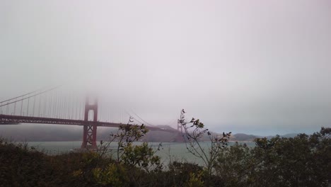 Gimbal-shot-panning-to-the-Golden-Gate-Bridge-enveloped-in-fog-from-the-Presidio-of-San-Francisco,-California