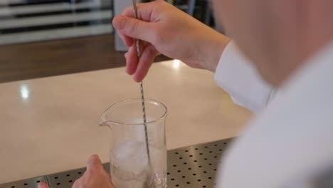 Bartender-stirs-the-ice-with-a-spiral-stirrer-on-a-glass