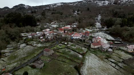 Snowy-village-with-vegetation-in-winter-under-a-cloudy-sky-in-Picornio,-a-town-in-Galicia