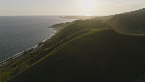Aerial-drone-shot-flies-left-from-a-green-mountain-to-passing-over-Pacific-Coast-Highway-PCH