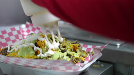 Adding-sour-cream-to-the-Carne-asada-smothered-fries---food-truck-series