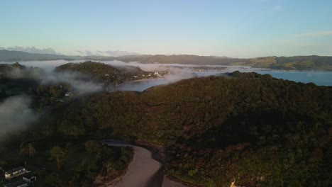 Cinematic-drone-flight-over-hills-with-fog-rolling-through-at-sunrise