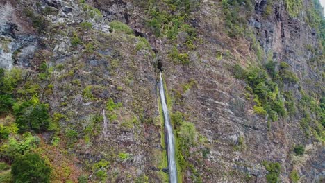 Drone-view-at-waterfall-next-to-road-and-ocean-in-Madeira