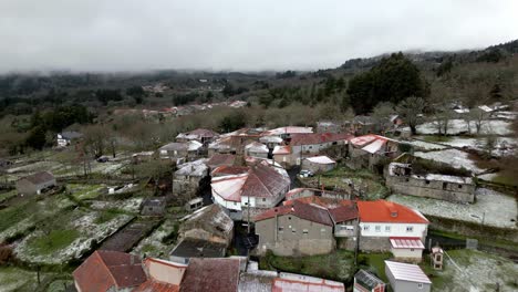 Snowy-village-with-vegetation-in-winter-under-a-cloudy-sky-in-Picornio,-a-village-in-Galicia